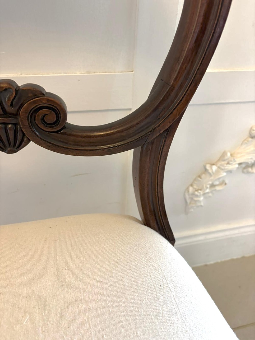 A set of ten antique English Regency mahogany dining chairs with carved balloon backs, cream upholstered seats, and turned front legs. View XIV