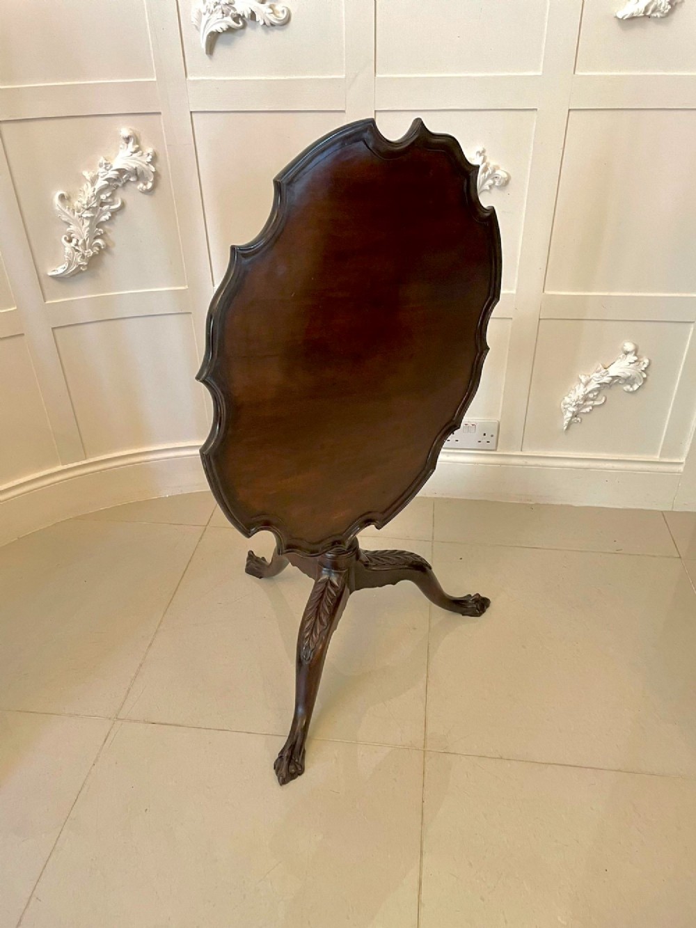 An antique George III mahogany tilt-top table featuring a scalloped pie-crust rim supported by a carved central pedestal and tripod cabriole legs. View VIII