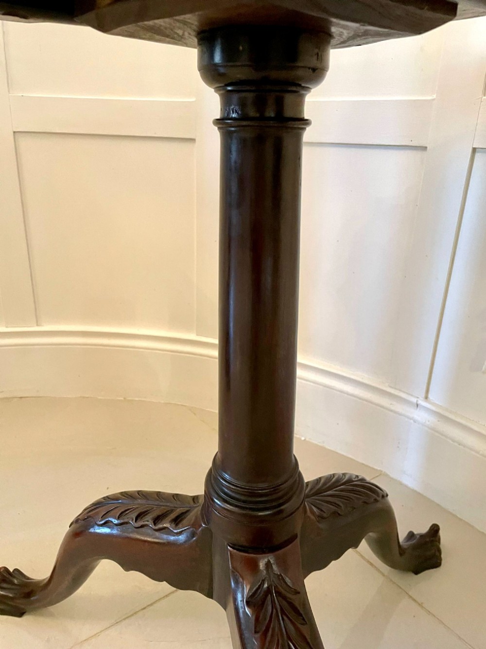 An antique George III mahogany tilt-top table featuring a scalloped pie-crust rim supported by a carved central pedestal and tripod cabriole legs. View X