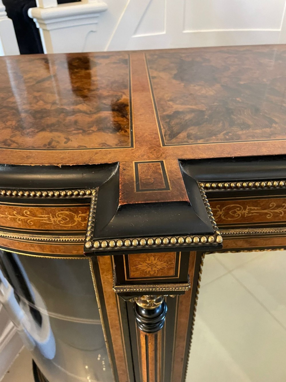 A Victorian burr walnut credenza featuring inlaid amboyna borders, central mirrored doors, curved side glass cabinets, and brass ormolu mounts. View II