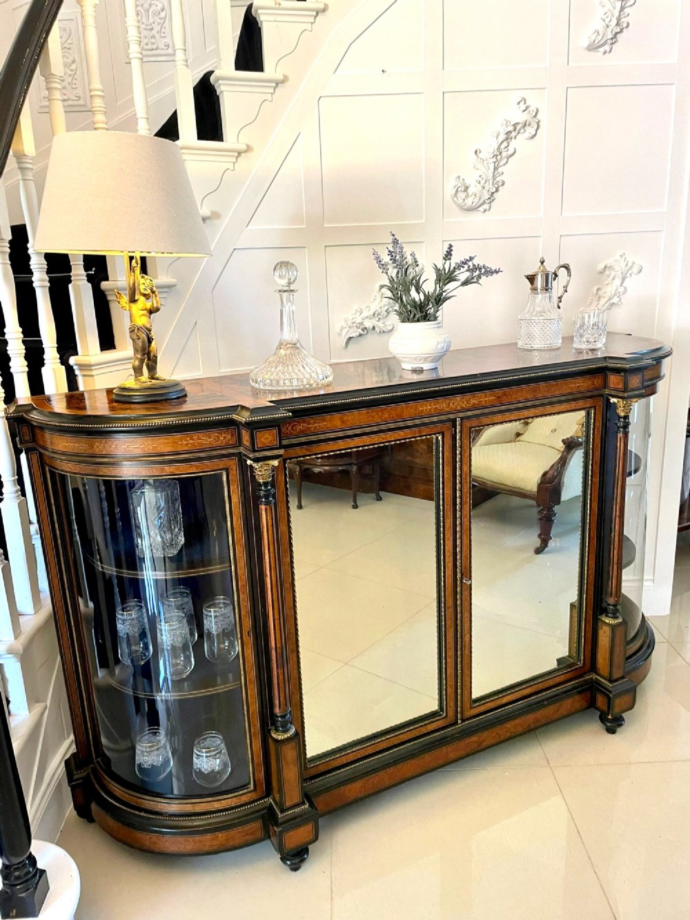 A Victorian burr walnut credenza featuring inlaid amboyna borders, central mirrored doors, curved side glass cabinets, and brass ormolu mounts. View IV