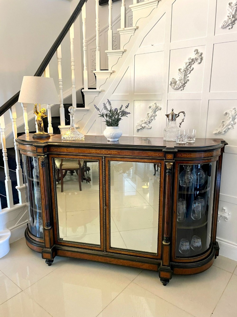 A Victorian burr walnut credenza featuring inlaid amboyna borders, central mirrored doors, curved side glass cabinets, and brass ormolu mounts. View V