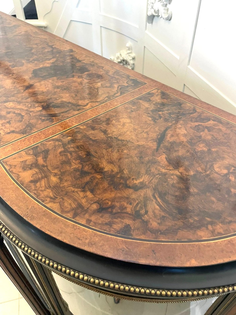 A Victorian burr walnut credenza featuring inlaid amboyna borders, central mirrored doors, curved side glass cabinets, and brass ormolu mounts. View VI
