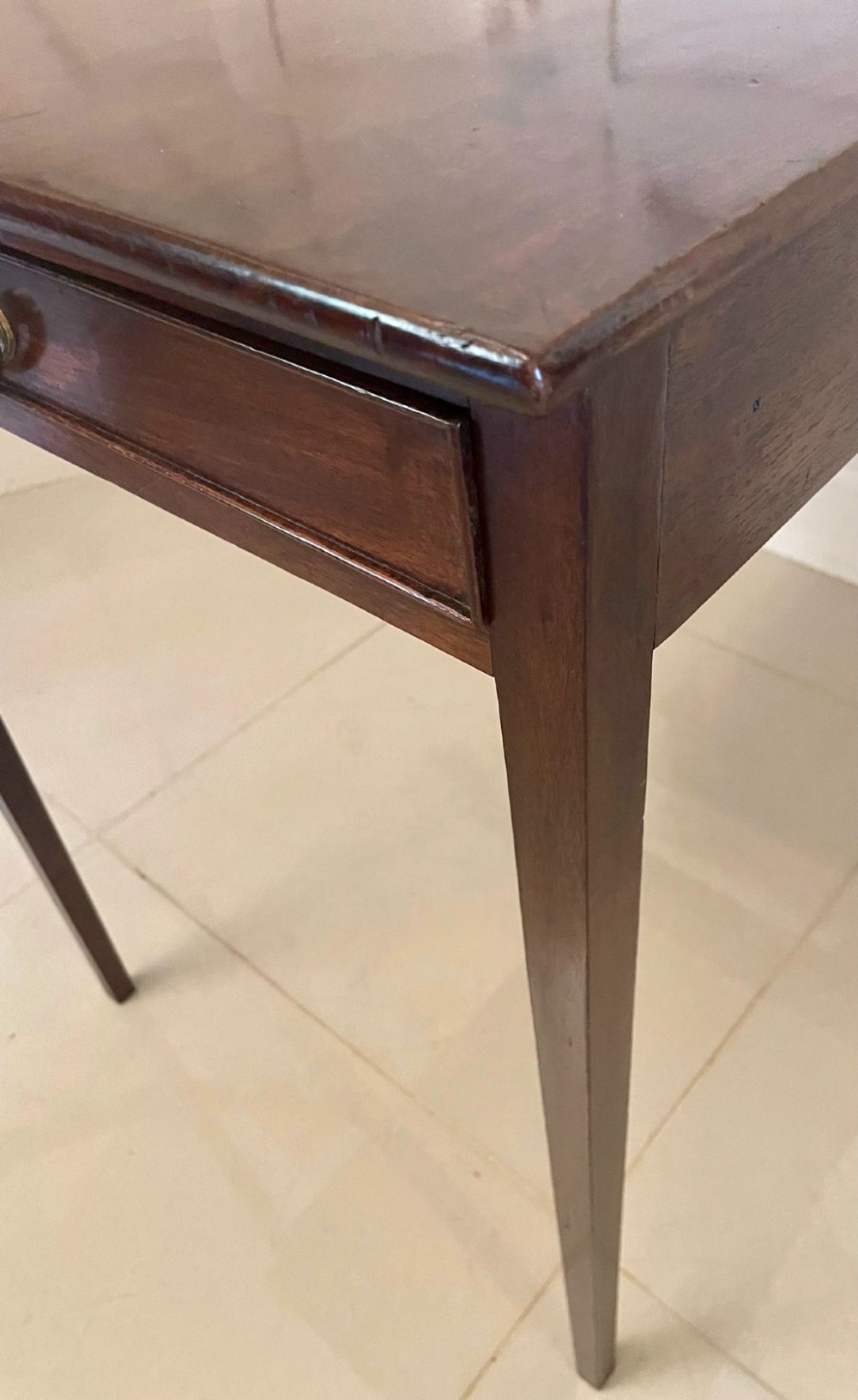 An antique George III mahogany side table featuring square tapered legs and a single side drawer with a brass handle. View V