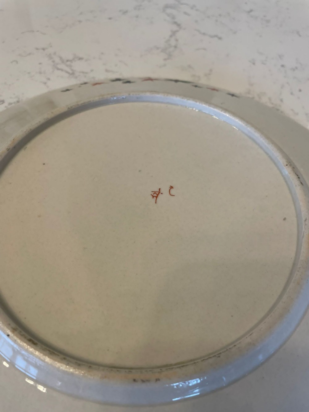 A shallow circular Japanese Kutani porcelain bowl featuring hand-painted floral chrysanthemum patterns, birds in flight, and detailed decorative borders in terracotta, red, black, and gold. View IX