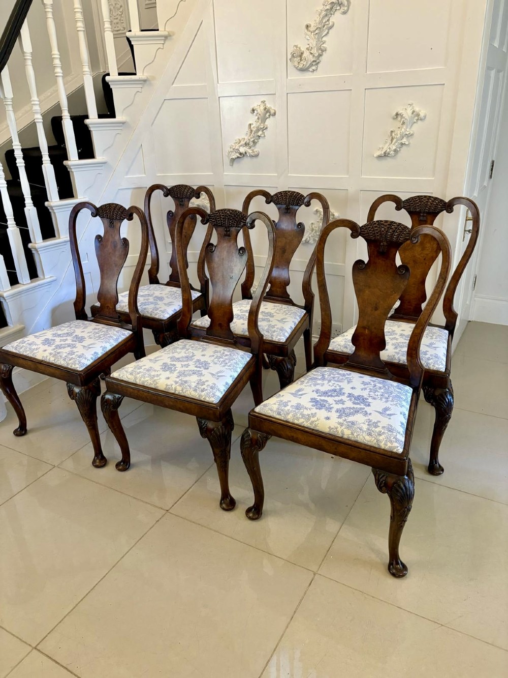 A set of six Victorian burr walnut dining chairs featuring carved top rails, vase-shaped splats, patterned upholstery, and cabriole legs.