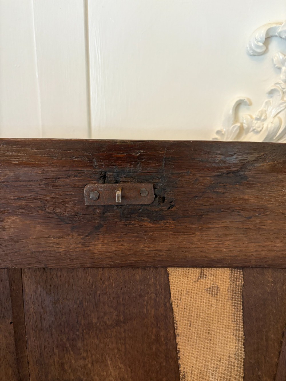 A 17th-century dark oak mule chest featuring a hinged paneled lid, a carved frieze above geometric front panels, and two lower drawers with wooden knobs. View IV