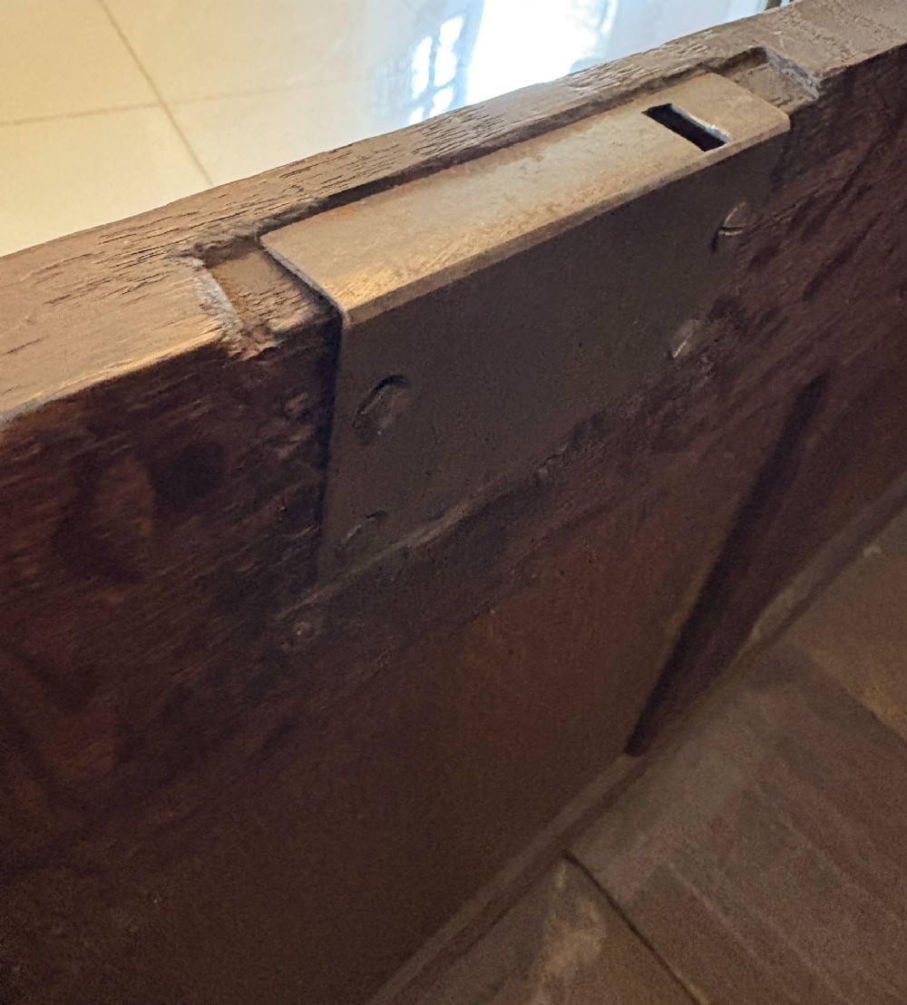 A 17th-century dark oak mule chest featuring a hinged paneled lid, a carved frieze above geometric front panels, and two lower drawers with wooden knobs. View VI