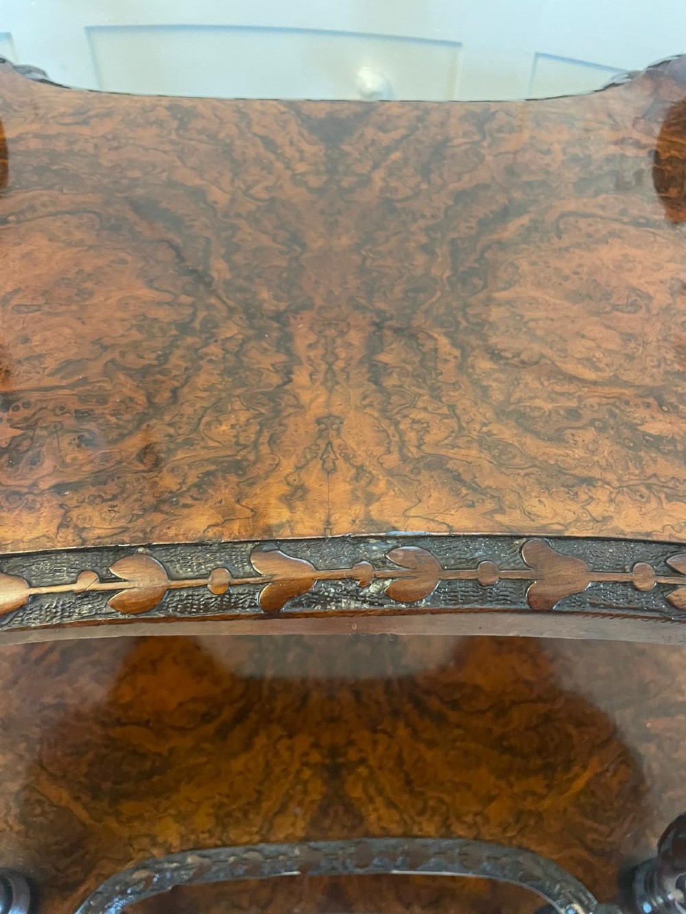 A Victorian burr walnut three-tier whatnot with intricately carved foliage uprights, finials, and serpentine-shaped shelves. View II