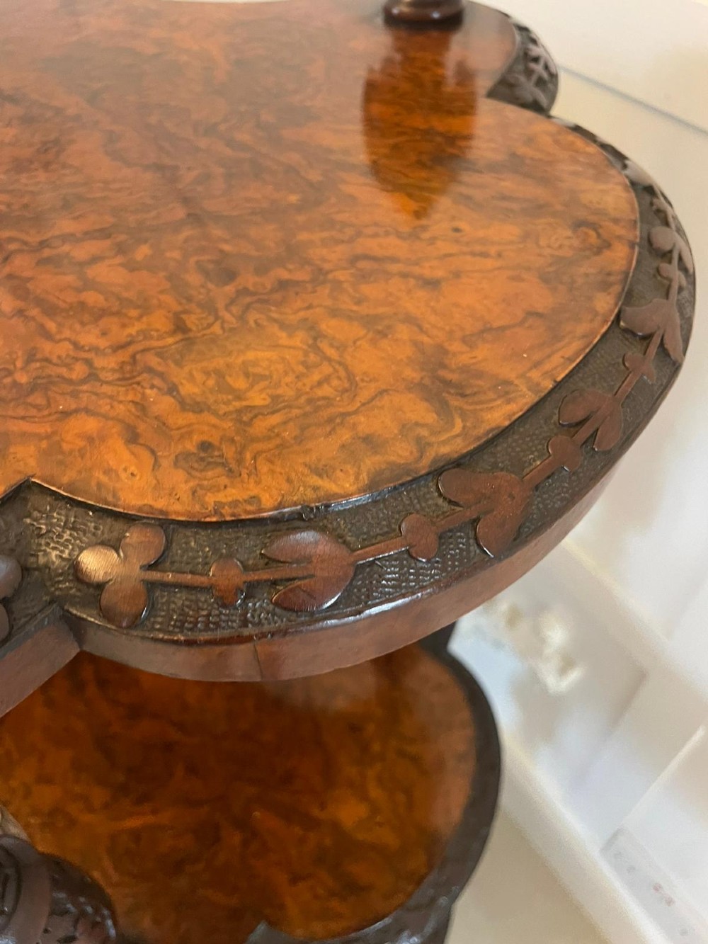 A Victorian burr walnut three-tier whatnot with intricately carved foliage uprights, finials, and serpentine-shaped shelves. View III