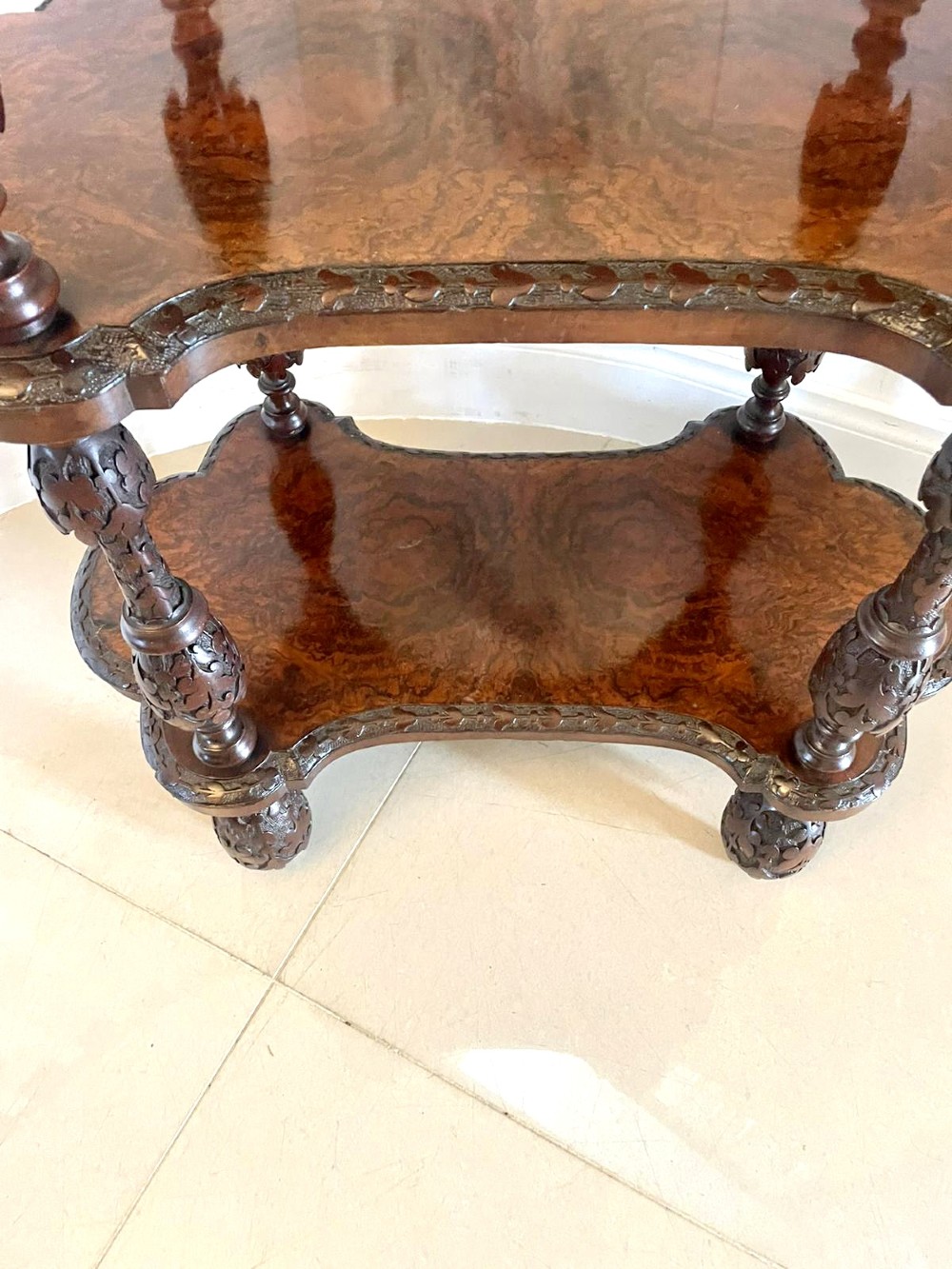 A Victorian burr walnut three-tier whatnot with intricately carved foliage uprights, finials, and serpentine-shaped shelves. View IV