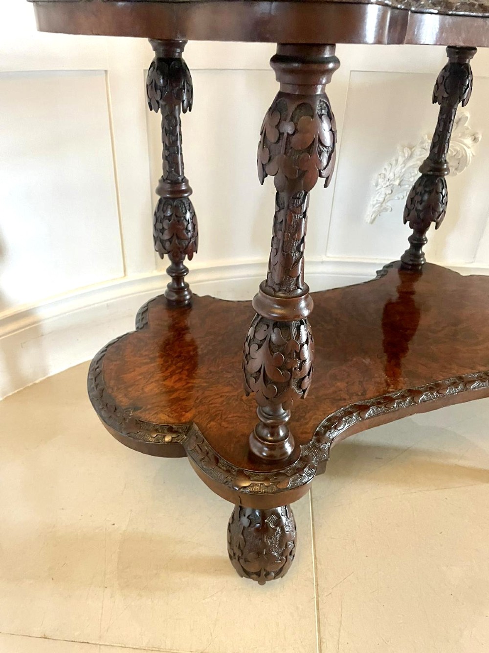 A Victorian burr walnut three-tier whatnot with intricately carved foliage uprights, finials, and serpentine-shaped shelves. View VIII