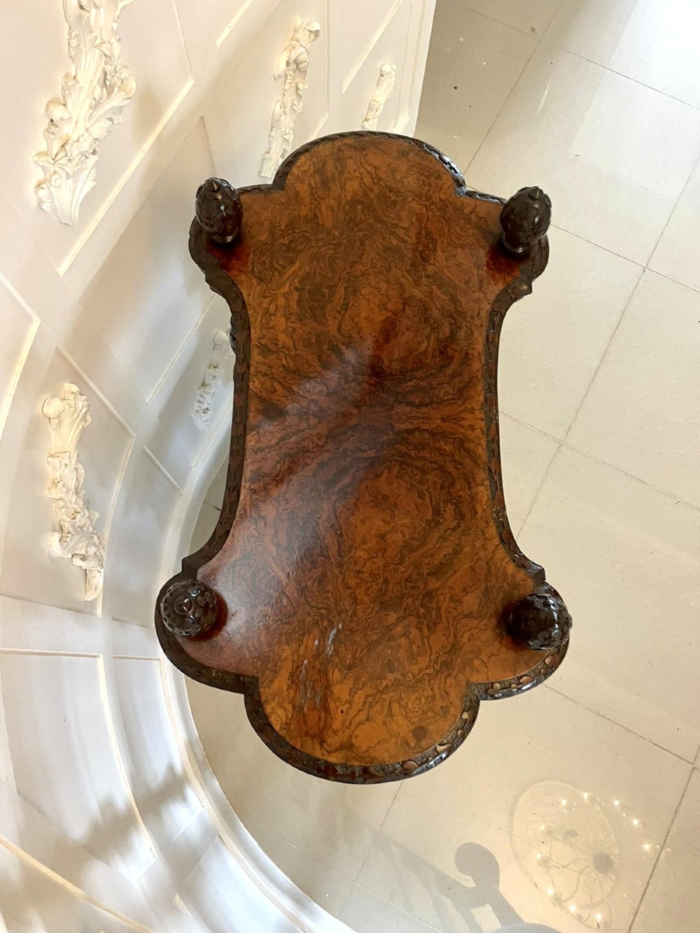 A Victorian burr walnut three-tier whatnot with intricately carved foliage uprights, finials, and serpentine-shaped shelves. View IX