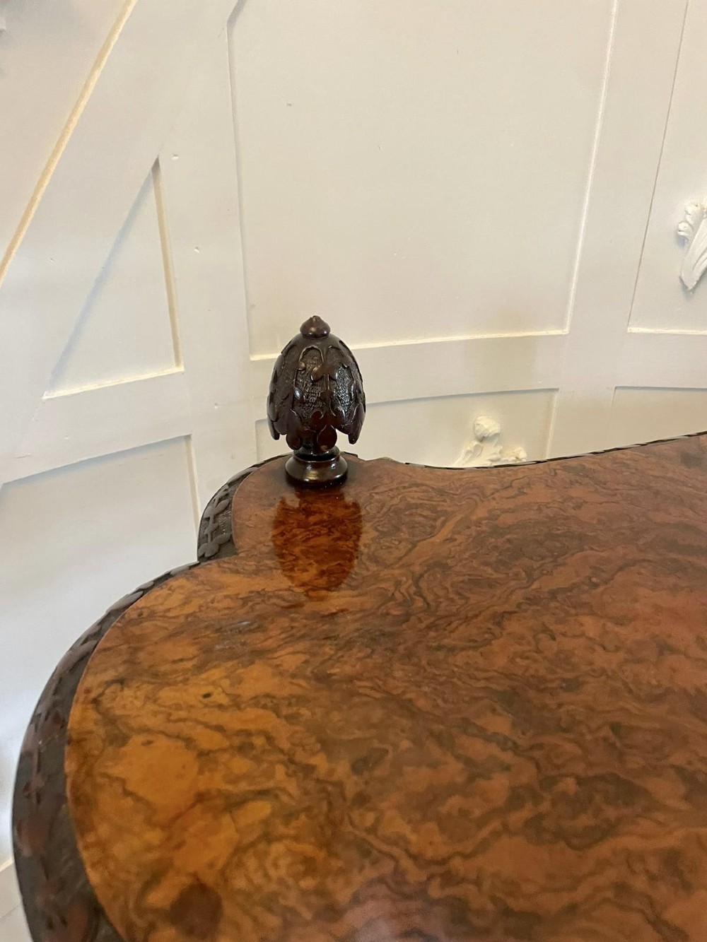 A Victorian burr walnut three-tier whatnot with intricately carved foliage uprights, finials, and serpentine-shaped shelves. View X