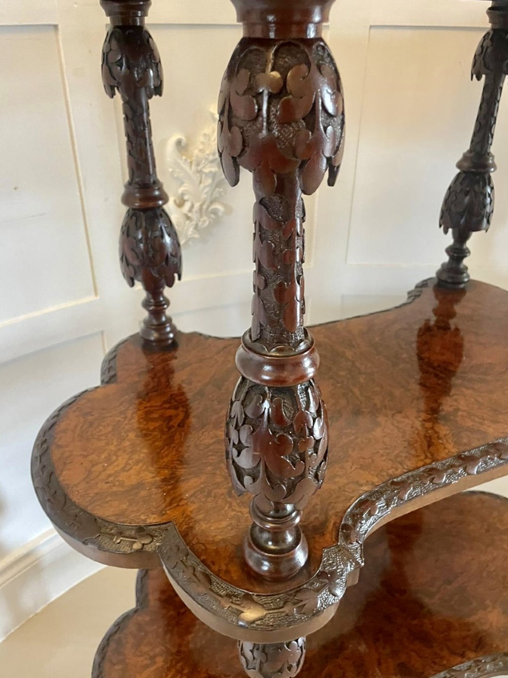 A Victorian burr walnut three-tier whatnot with intricately carved foliage uprights, finials, and serpentine-shaped shelves. View XI