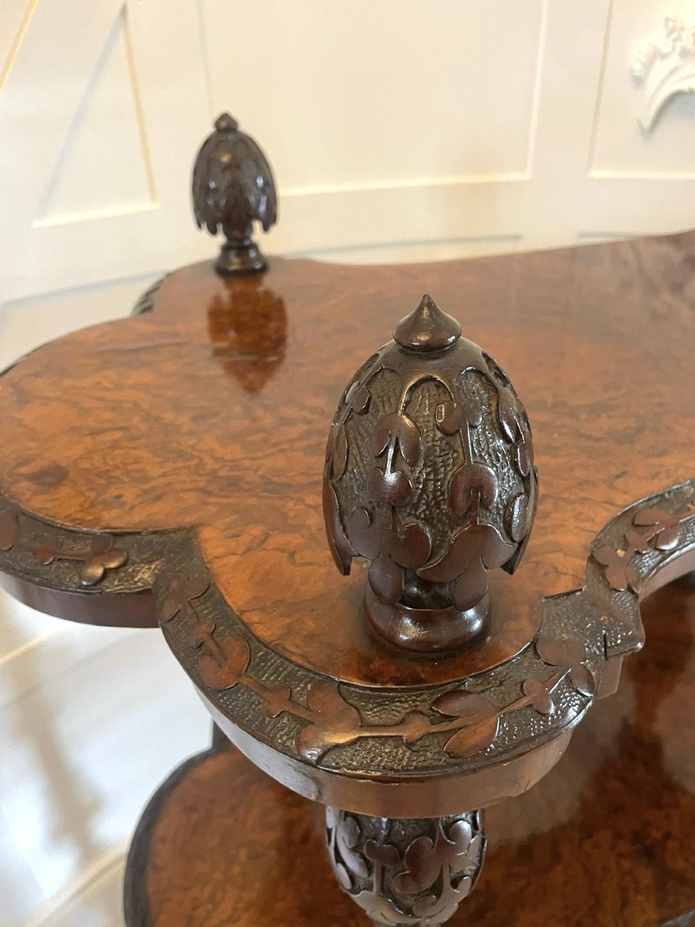 A Victorian burr walnut three-tier whatnot with intricately carved foliage uprights, finials, and serpentine-shaped shelves. View XIII