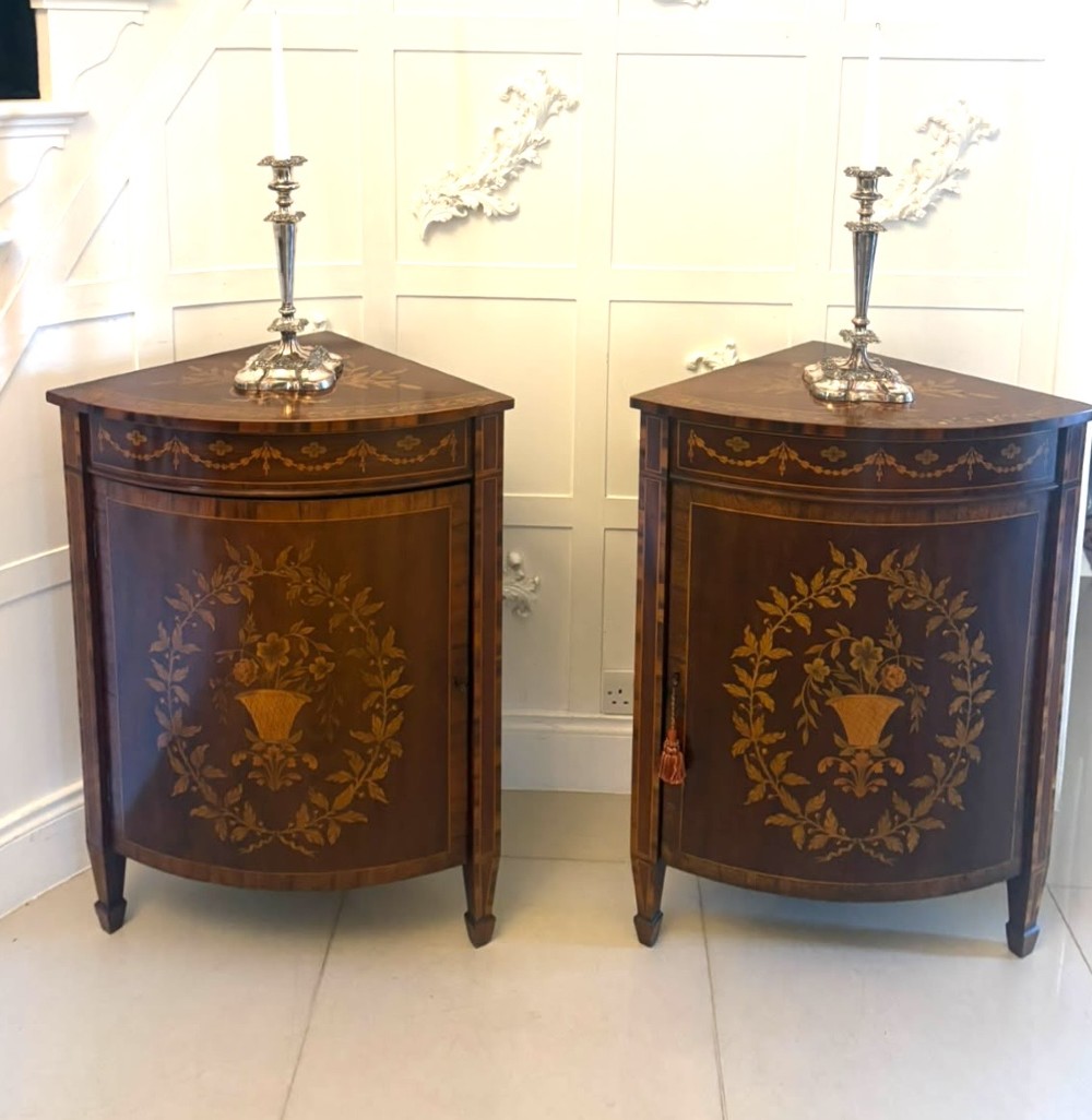 A pair of Victorian mahogany corner cabinets featuring curved bow fronts with floral urn marquetry inlays and tapered square feet. View VI
