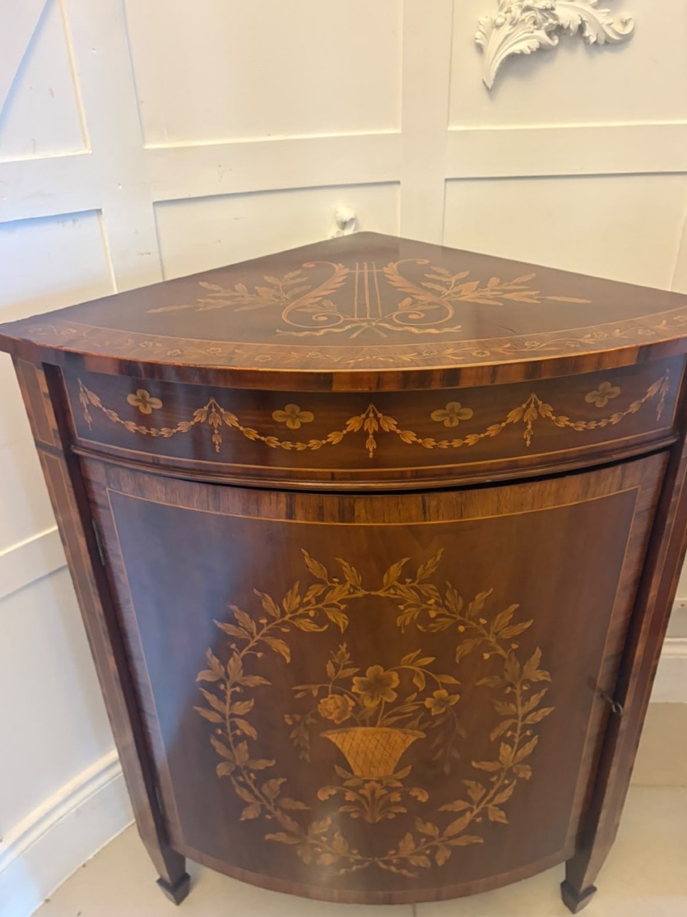 A pair of Victorian mahogany corner cabinets featuring curved bow fronts with floral urn marquetry inlays and tapered square feet. View VIII