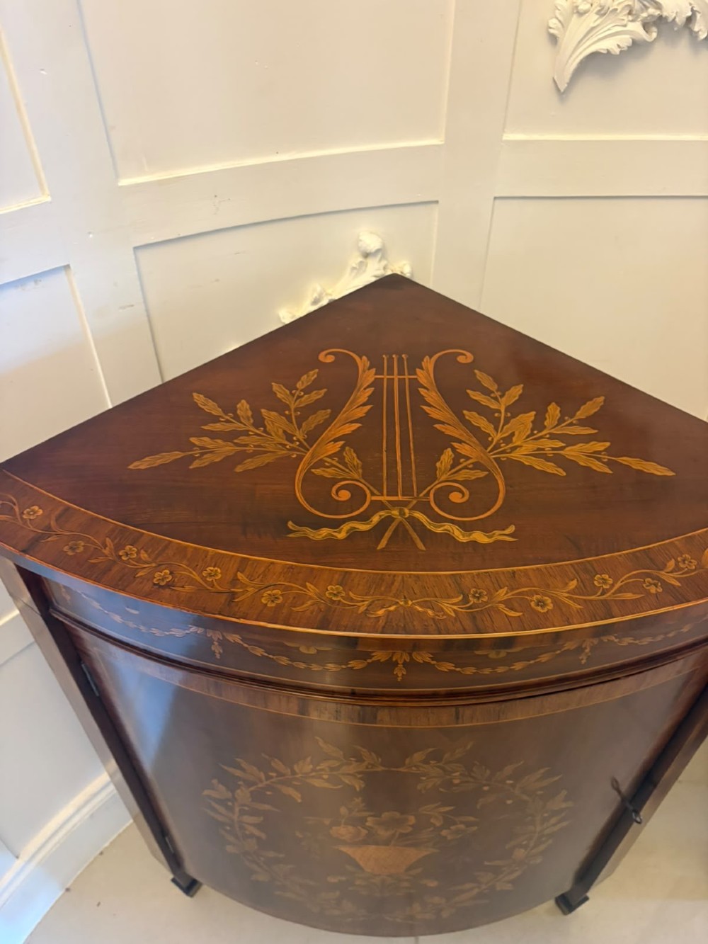 A pair of Victorian mahogany corner cabinets featuring curved bow fronts with floral urn marquetry inlays and tapered square feet. View IX