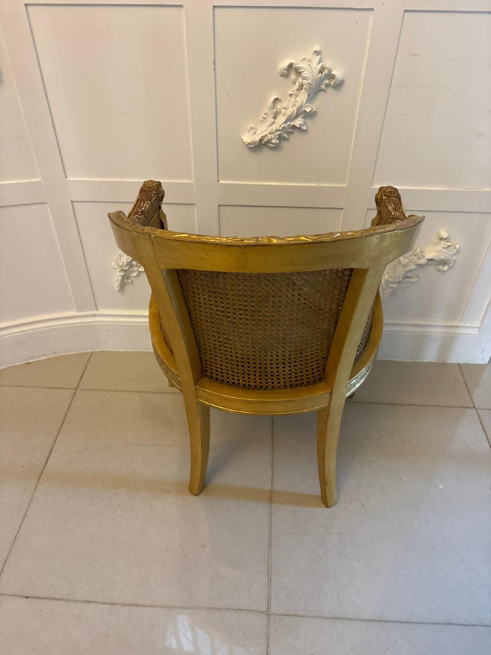 A pair of French Louis XVI style carved giltwood tub armchairs featuring curved caned backs and dark blue velvet seat cushions. View VI