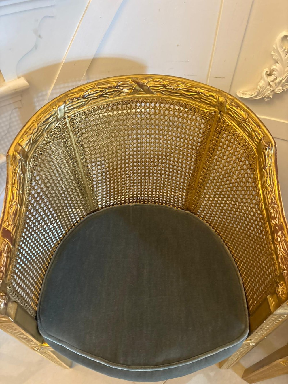 A pair of French Louis XVI style carved giltwood tub armchairs featuring curved caned backs and dark blue velvet seat cushions. View XIII
