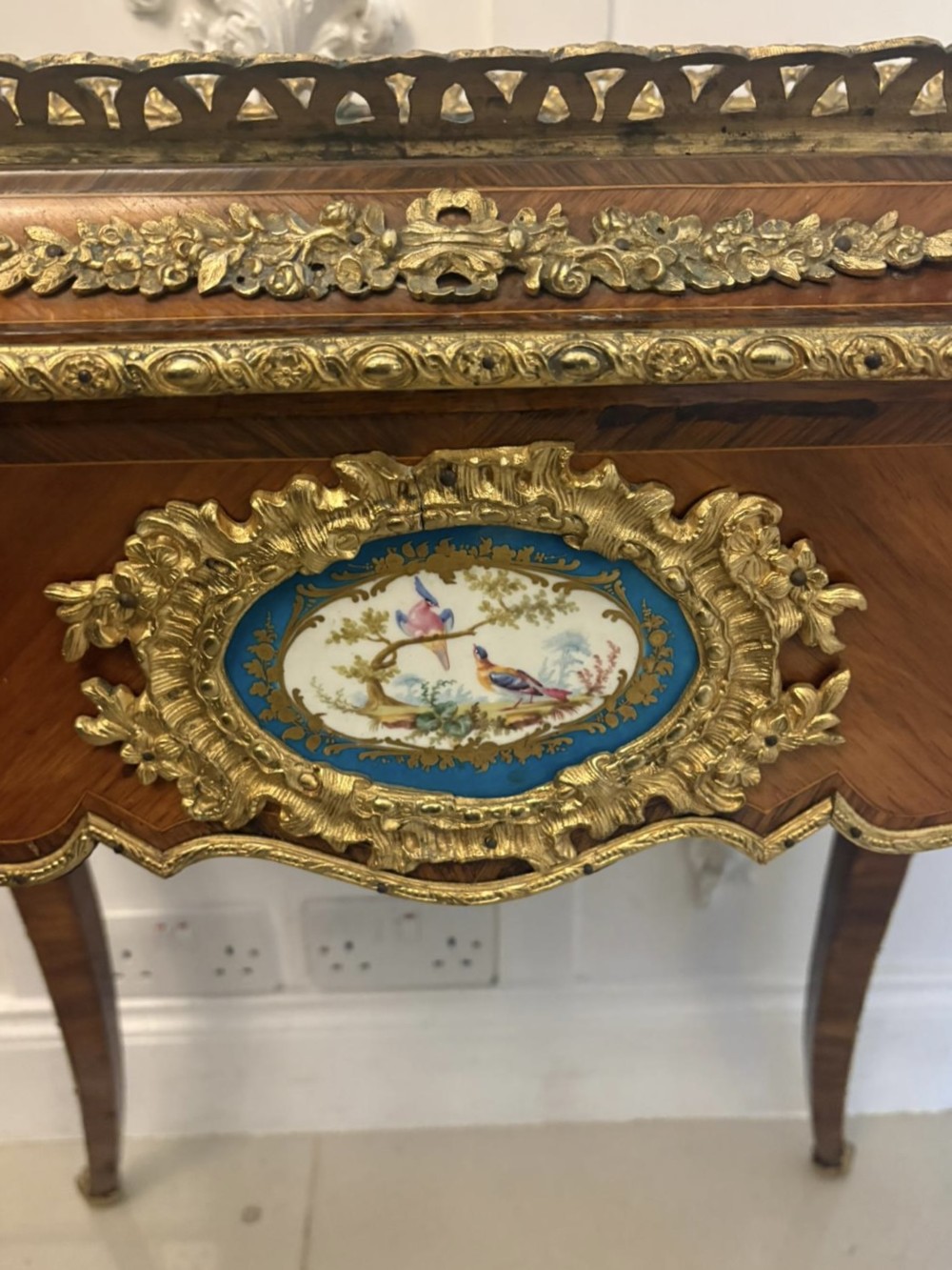 A Louis XV style kingwood jardiniere stand with ornate gilt-bronze ormolu mounts, cabriole legs, and a central porcelain plaque. View VII