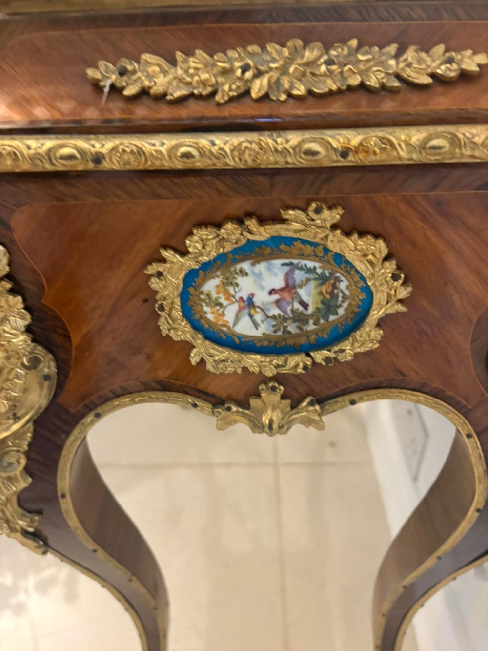 A Louis XV style kingwood jardiniere stand with ornate gilt-bronze ormolu mounts, cabriole legs, and a central porcelain plaque. View X