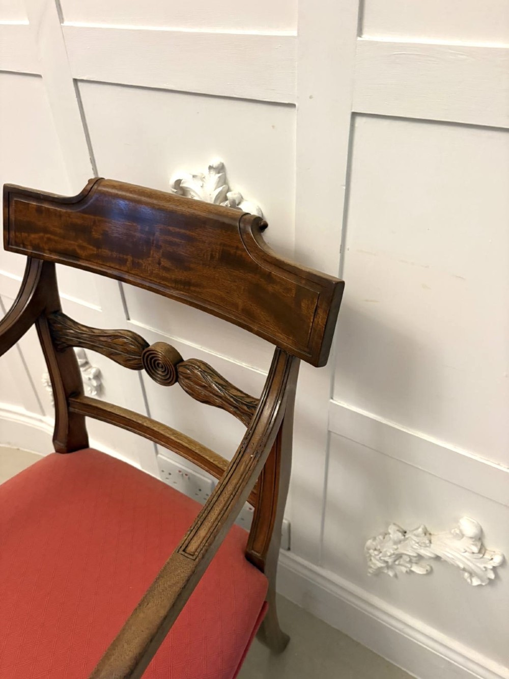 A set of twelve Regency mahogany dining chairs with carved mid-rails and coral fabric upholstered seats, including two matching carver armchairs. View II