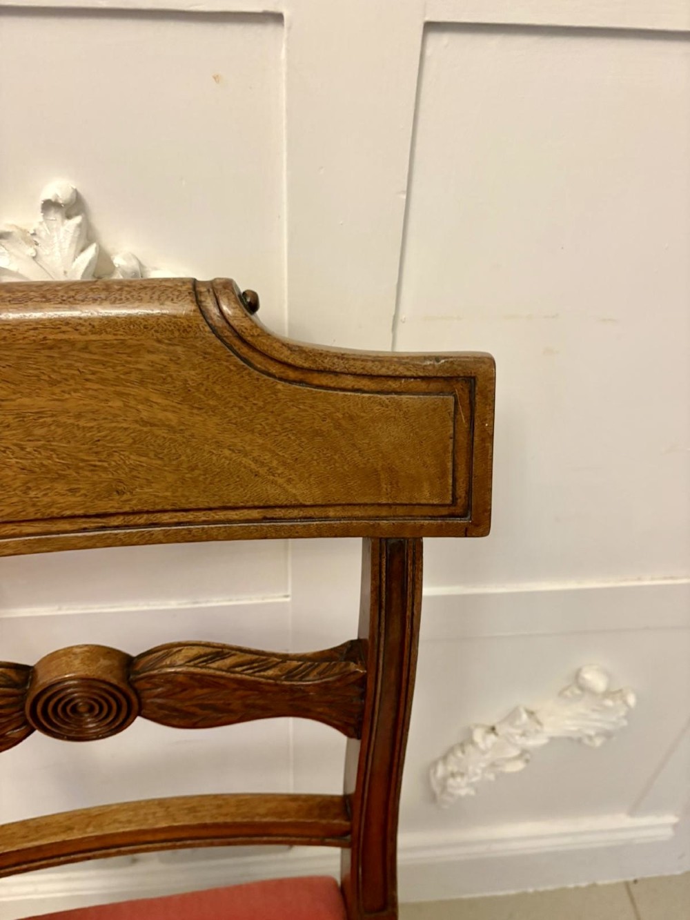 A set of twelve Regency mahogany dining chairs with carved mid-rails and coral fabric upholstered seats, including two matching carver armchairs. View VI