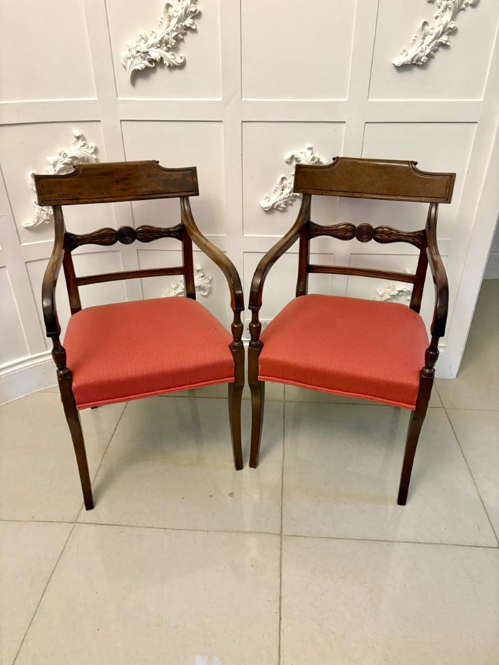 A set of twelve Regency mahogany dining chairs with carved mid-rails and coral fabric upholstered seats, including two matching carver armchairs. View VII