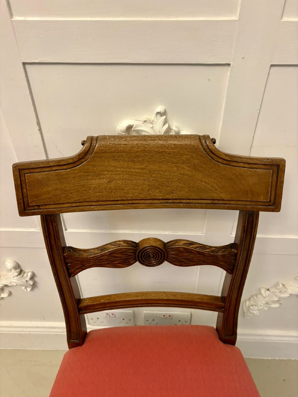 A set of twelve Regency mahogany dining chairs with carved mid-rails and coral fabric upholstered seats, including two matching carver armchairs. View VIII