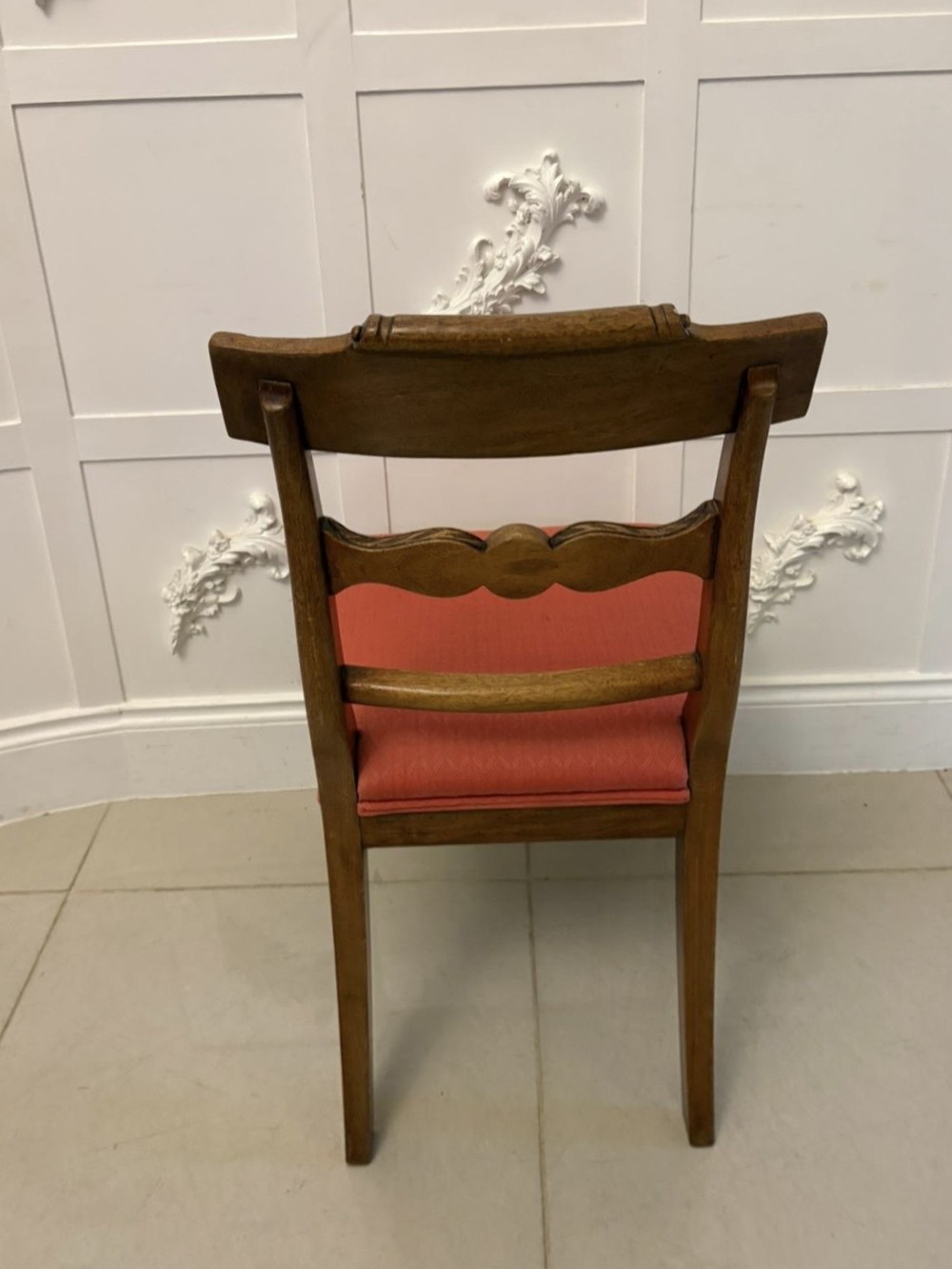 A set of twelve Regency mahogany dining chairs with carved mid-rails and coral fabric upholstered seats, including two matching carver armchairs. View XII