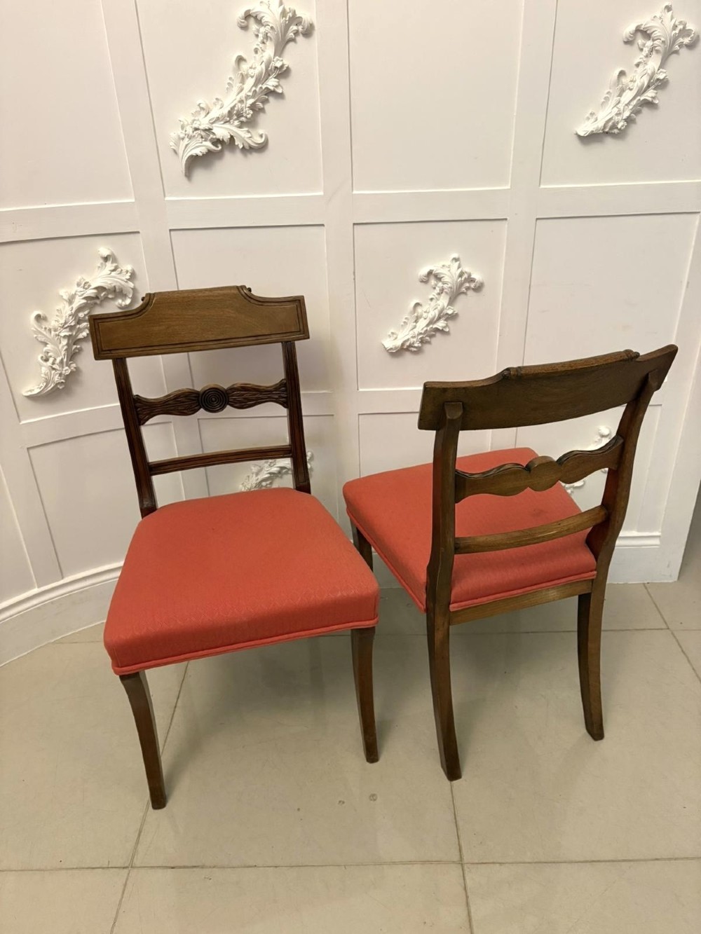 A set of twelve Regency mahogany dining chairs with carved mid-rails and coral fabric upholstered seats, including two matching carver armchairs. View XV