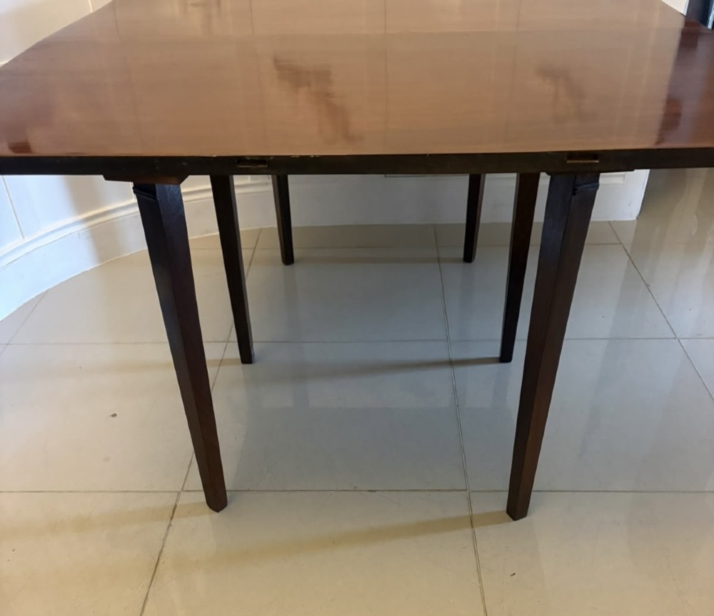 An antique Georgian mahogany drop-leaf dining table shown folded closed with square straight legs and a polished dark wood surface. View X