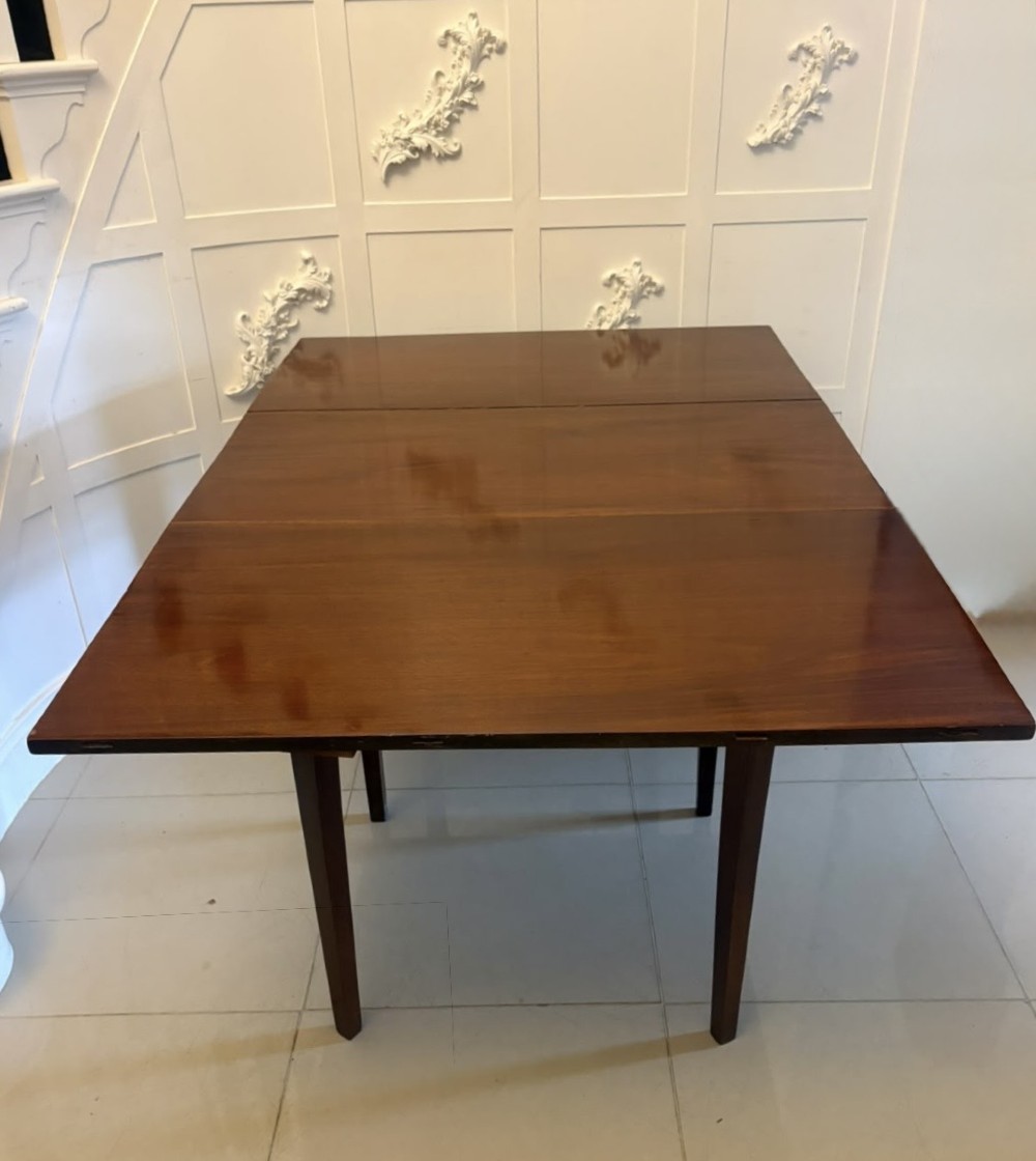 An antique Georgian mahogany drop-leaf dining table shown folded closed with square straight legs and a polished dark wood surface. View XIII