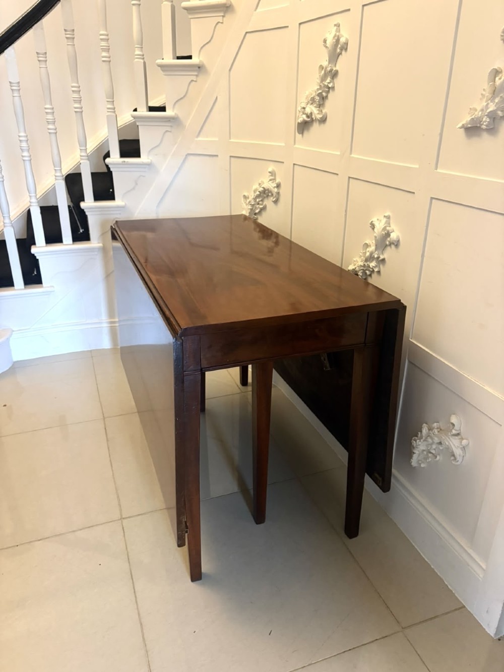 An antique Georgian mahogany drop-leaf dining table shown folded closed with square straight legs and a polished dark wood surface. View XIV