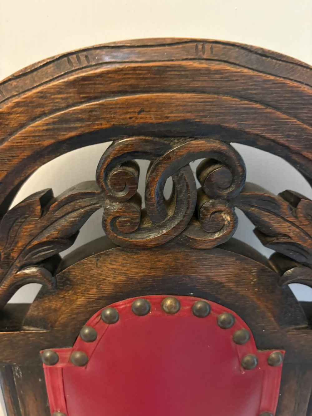 A set of high-backed dark oak dining chairs with barley twist uprights, carved cresting rails, and red upholstered seats and back panels with stud trim. View II