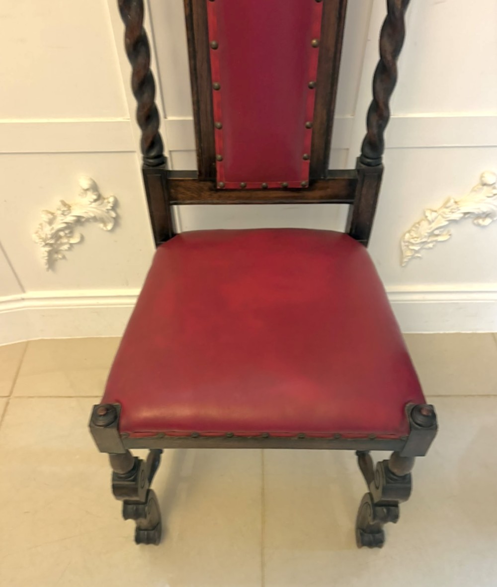 A set of high-backed dark oak dining chairs with barley twist uprights, carved cresting rails, and red upholstered seats and back panels with stud trim. View III