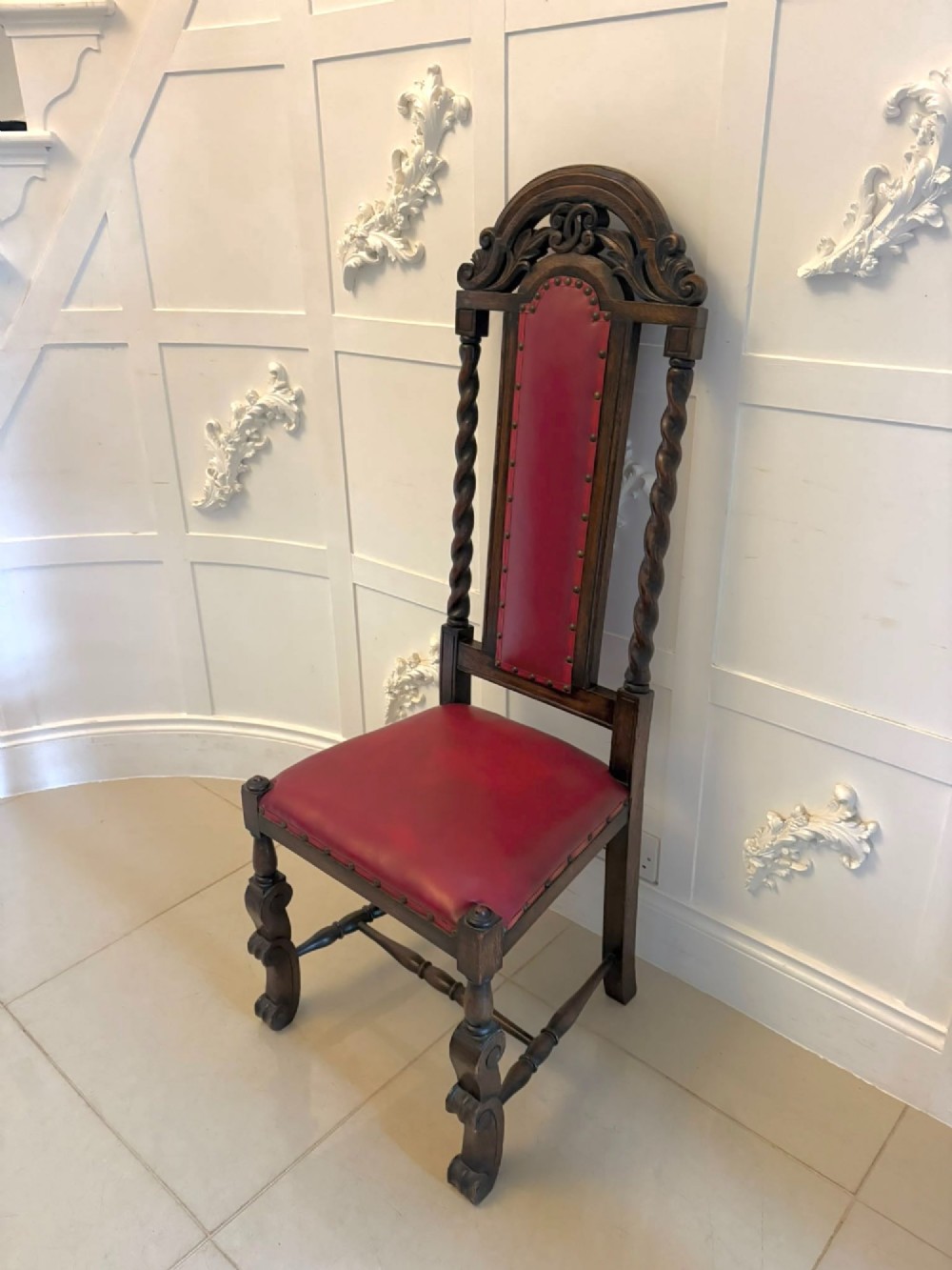 A set of high-backed dark oak dining chairs with barley twist uprights, carved cresting rails, and red upholstered seats and back panels with stud trim. View VIII