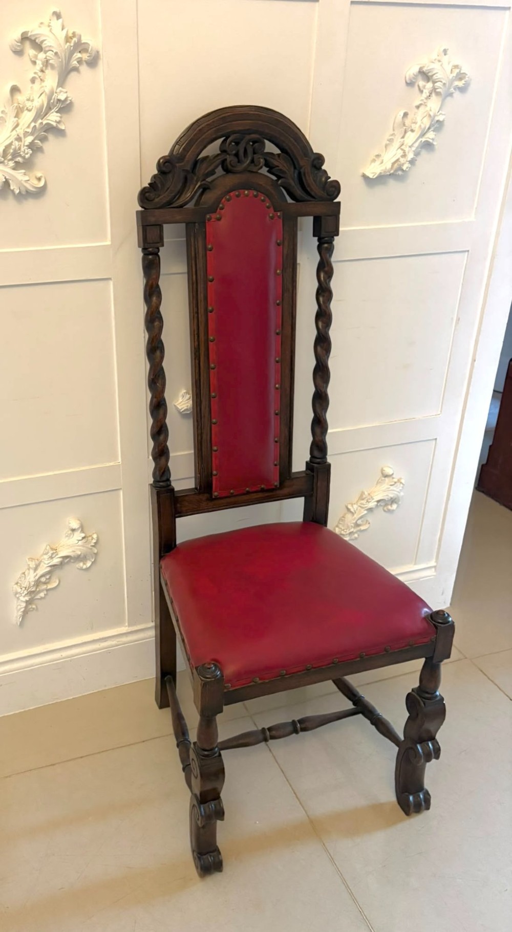 A set of high-backed dark oak dining chairs with barley twist uprights, carved cresting rails, and red upholstered seats and back panels with stud trim. View X