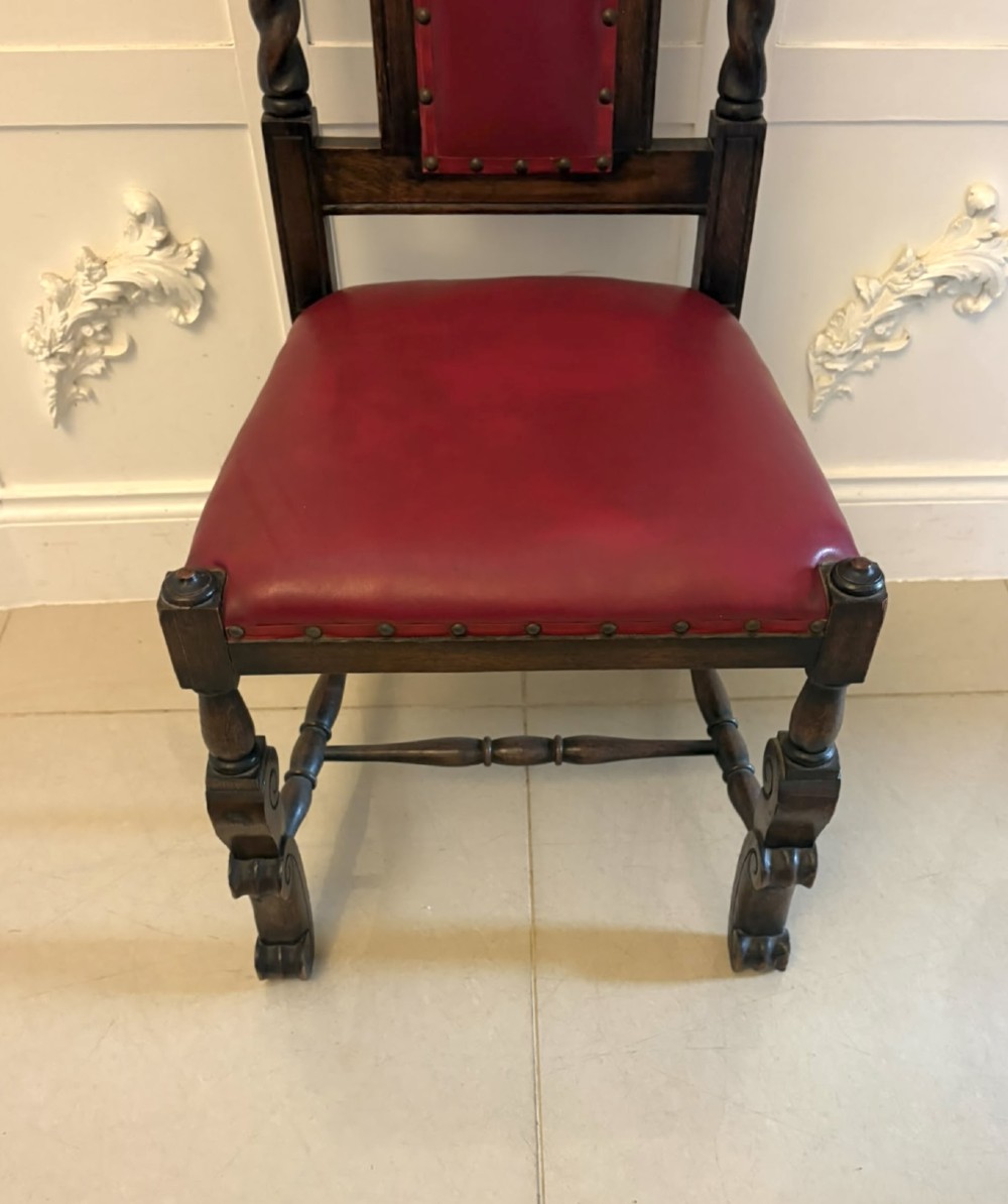 A set of high-backed dark oak dining chairs with barley twist uprights, carved cresting rails, and red upholstered seats and back panels with stud trim. View XIII