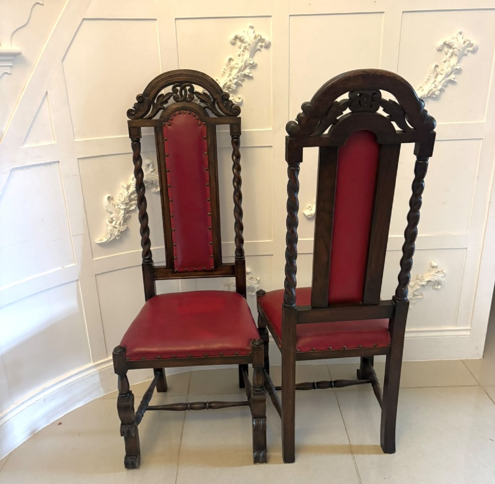 A set of high-backed dark oak dining chairs with barley twist uprights, carved cresting rails, and red upholstered seats and back panels with stud trim. View XV