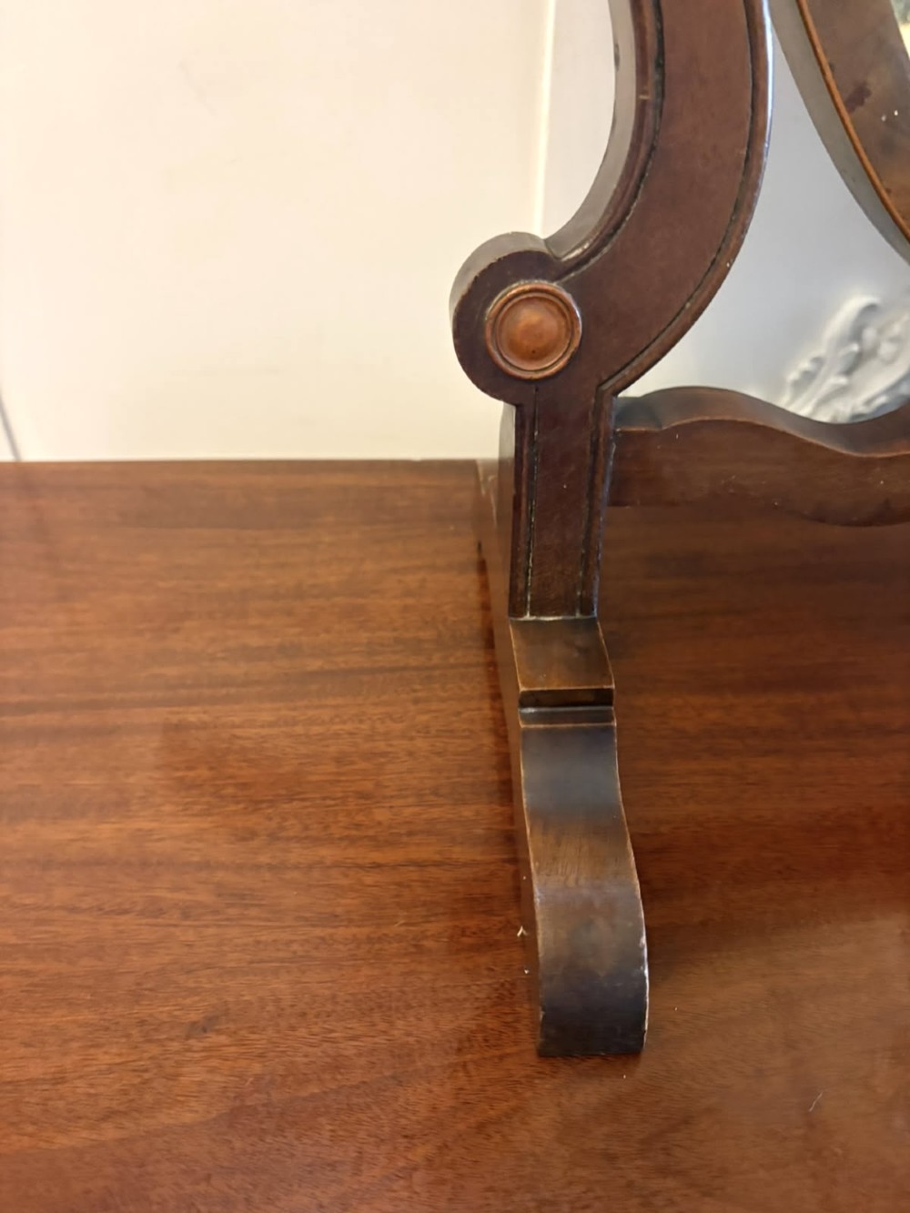 An Edwardian mahogany toilet mirror featuring a shield-shaped frame with bevelled glass mounted on a swivelling stand with brass knobs. View X