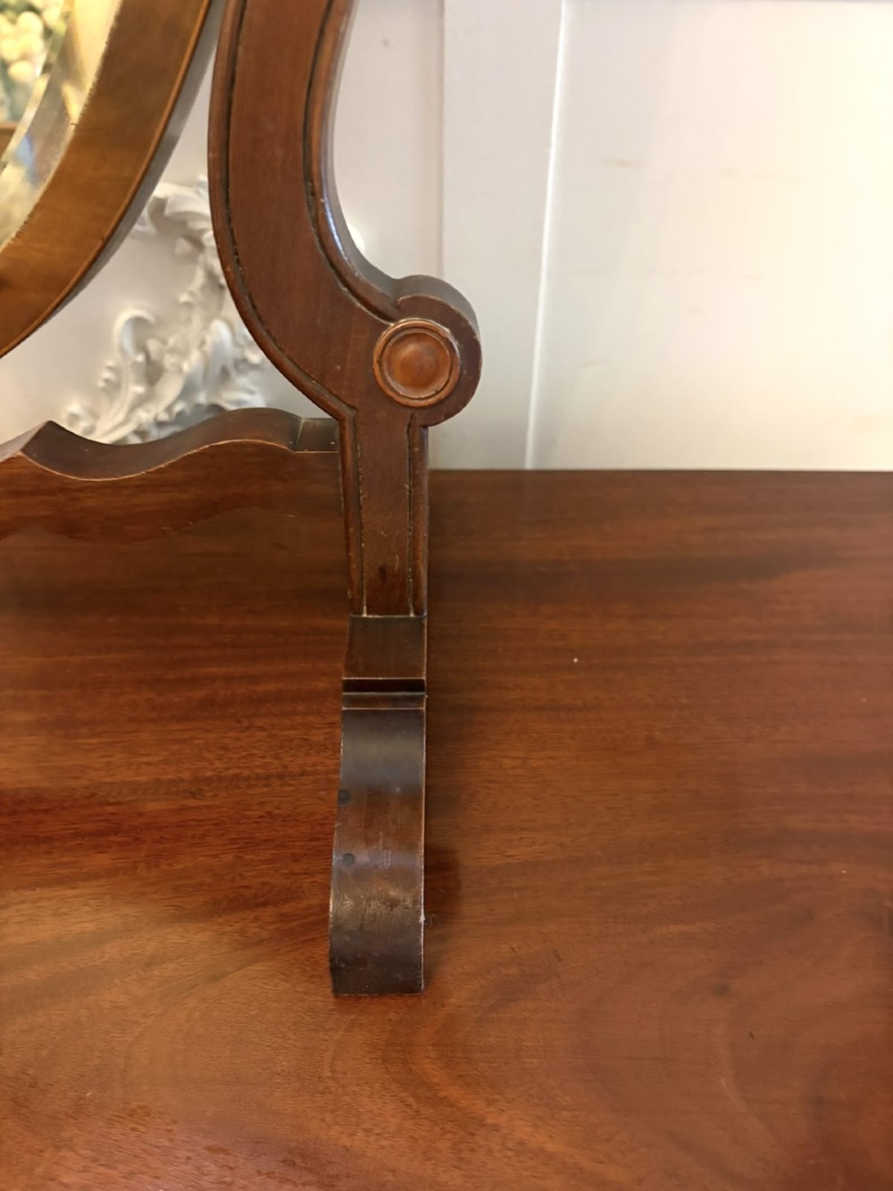 An Edwardian mahogany toilet mirror featuring a shield-shaped frame with bevelled glass mounted on a swivelling stand with brass knobs. View XI