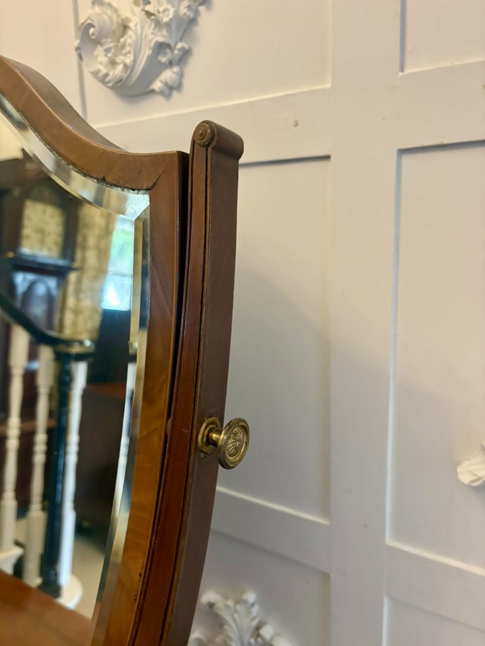 An Edwardian mahogany toilet mirror featuring a shield-shaped frame with bevelled glass mounted on a swivelling stand with brass knobs. View XII