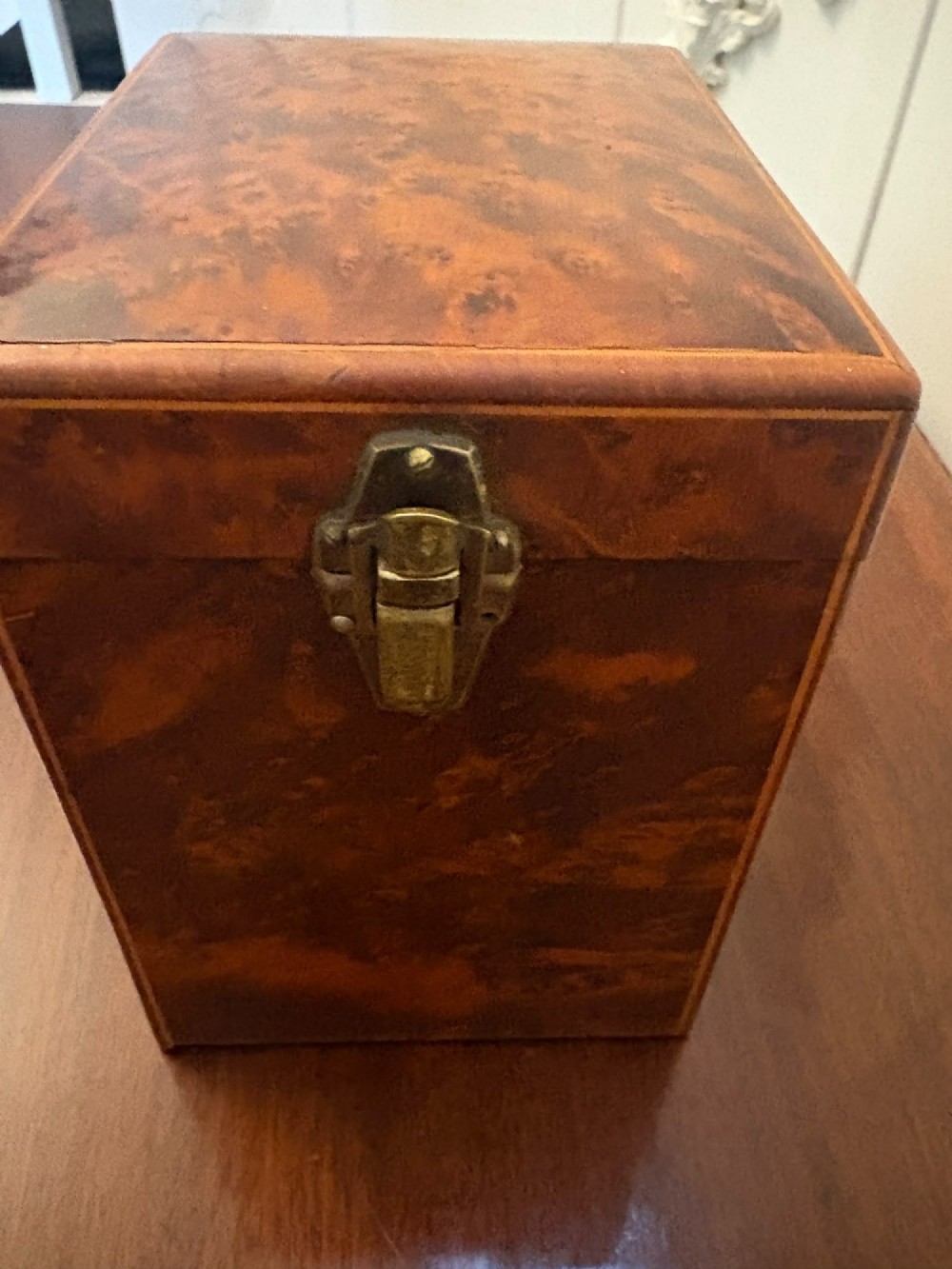 An upright Victorian travelling tea caddy crafted from amboyna burl wood with line inlay and a brass front latch. View IV