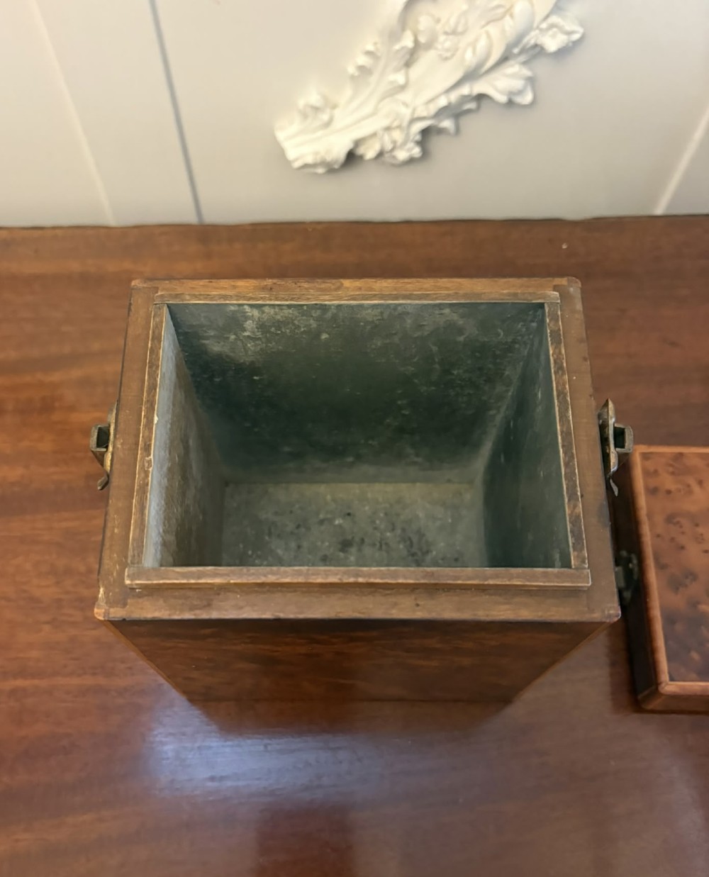 An upright Victorian travelling tea caddy crafted from amboyna burl wood with line inlay and a brass front latch. View V