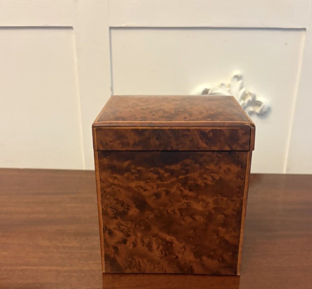 An upright Victorian travelling tea caddy crafted from amboyna burl wood with line inlay and a brass front latch. View X