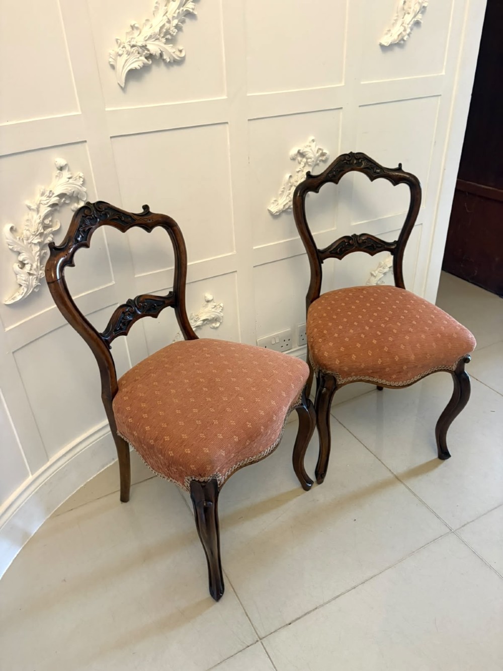 A pair of Victorian carved walnut side chairs featuring open balloon backs with foliate carvings, cabriole legs, and terracotta patterned fabric upholstered seats. View IV