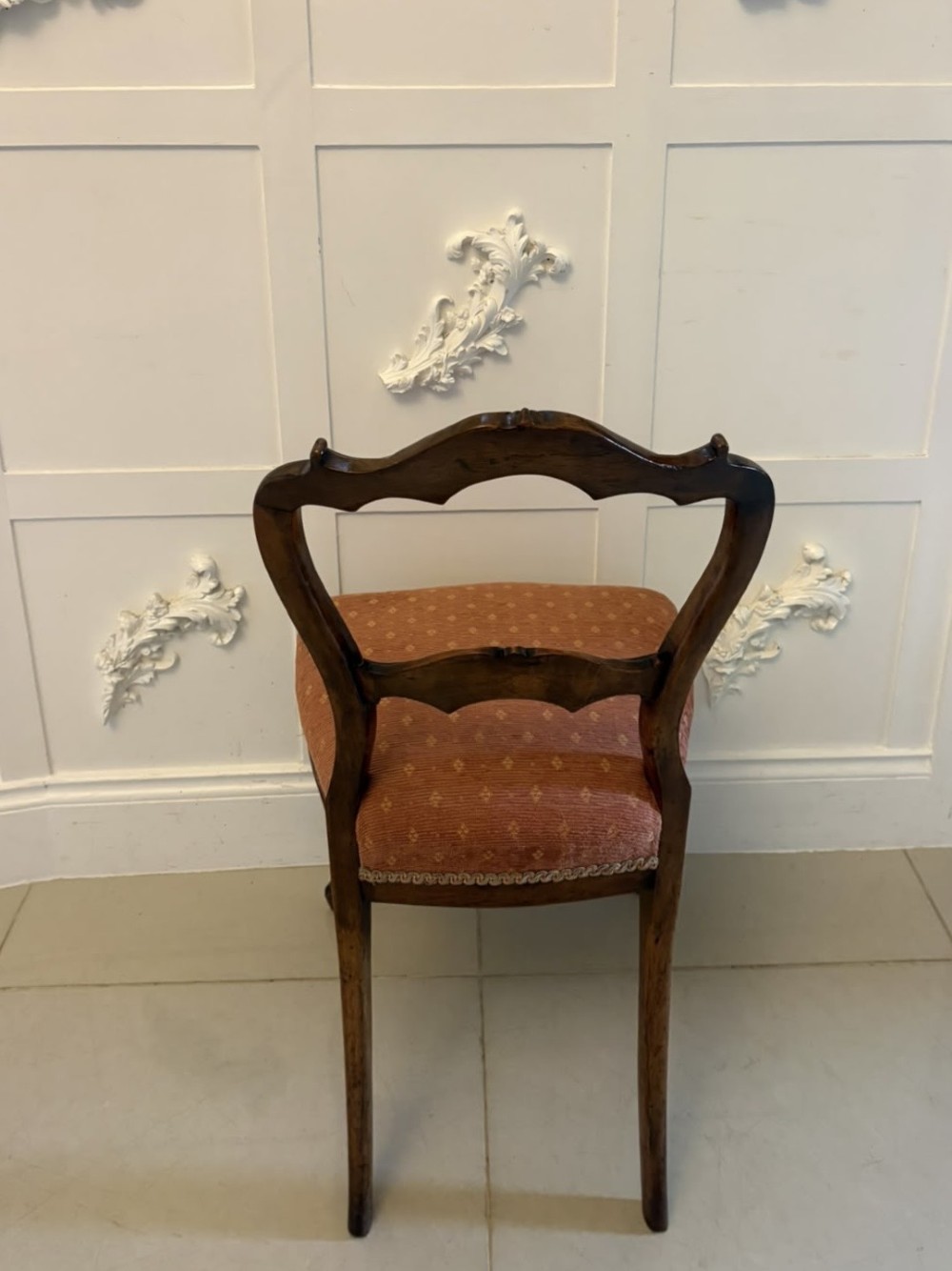 A pair of Victorian carved walnut side chairs featuring open balloon backs with foliate carvings, cabriole legs, and terracotta patterned fabric upholstered seats. View VII